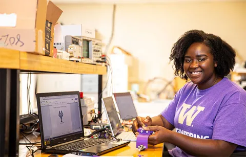 Ewurama Karikari sitting in front of laptops in a lab