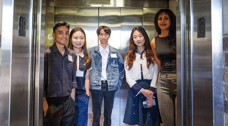 Students posing for picture, standing inside elevator