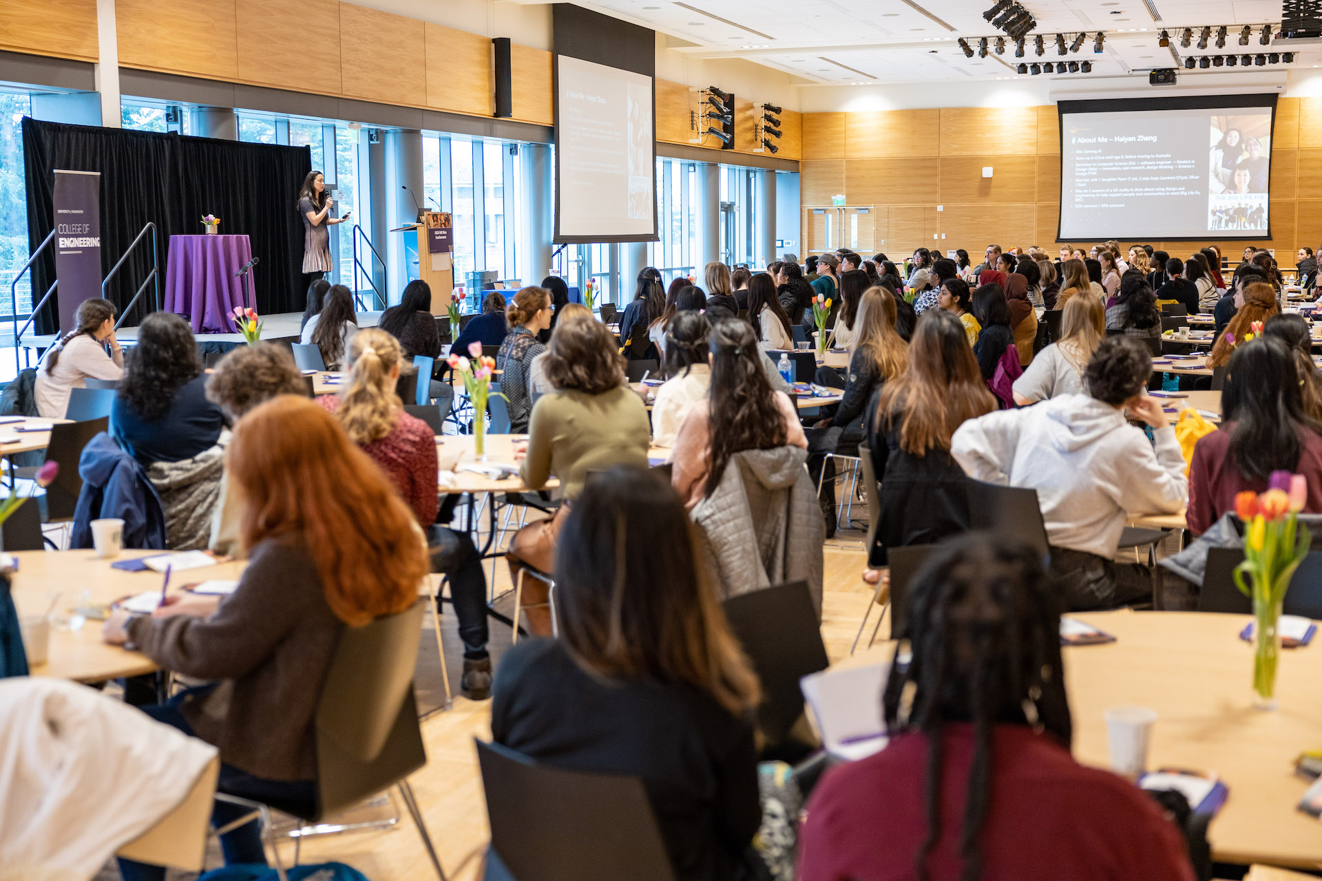 Wide shot of people sitting in a room during a speaker presentation