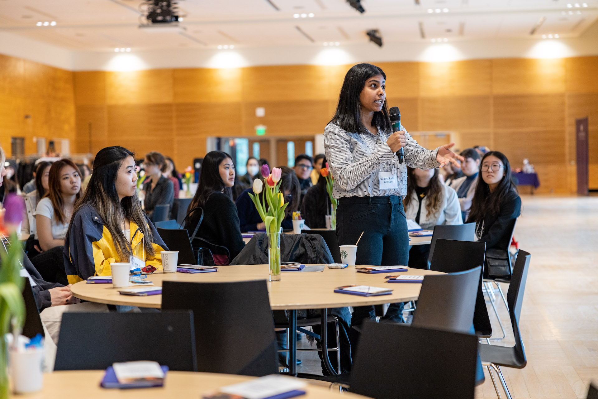 a person speaking into a microphone in front of a group of people