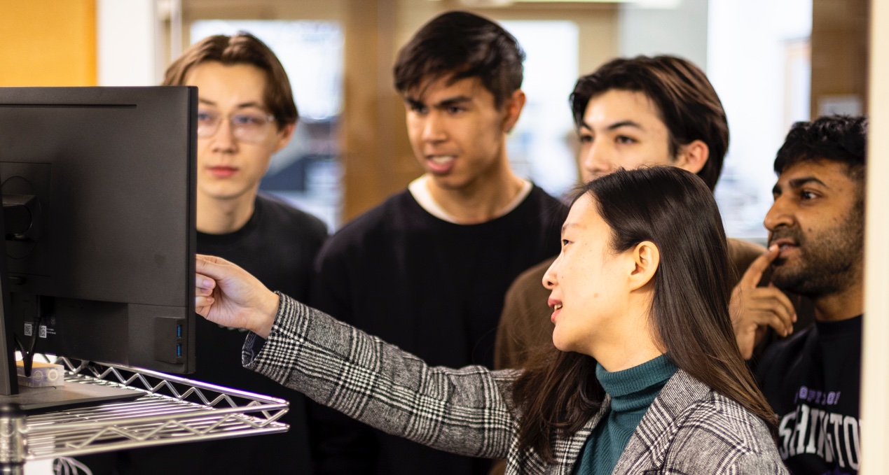 A group of students being shown something on a screen by a professor