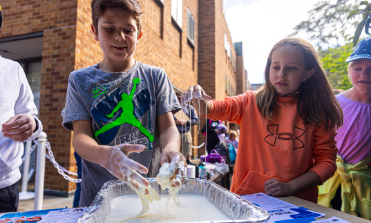 Grade school students using their hands to play with liquid goop