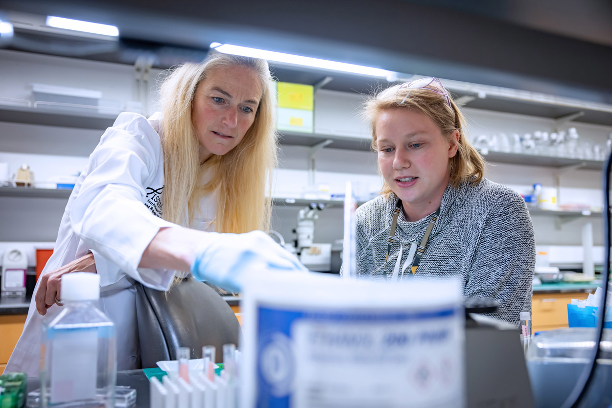 Two women working together in a laboratory, surrounded by scientific equipment.