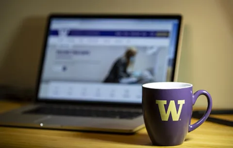 coffee mug next to a laptop on a table