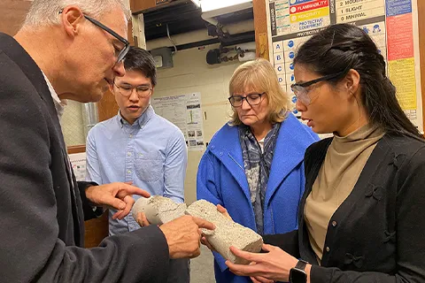 MSE master's students Kunthea Deng and Renjie Song show Gov. Jay Inslee and his wife, Trudi, how samples of zeolite concrete fractured in compression tests.