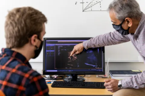 Mike Averkiou and doctoral student Connor Krolak reviewing ultrasound images of tumor perfusion with microbubbles from a patient study. Photo by Dennis Wise.