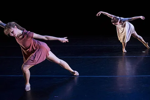 Two dancers performing with their arms outstretched