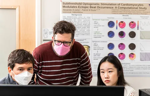 Boyle and two researchers looking at a computer monitor