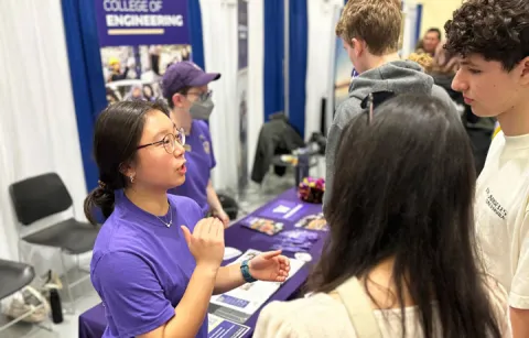 Engineering student talking to other students at fair