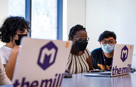 A group of students sitting in front of laptops