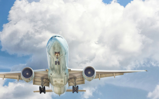 A commercial airplane from below against a partly cloudy sky.