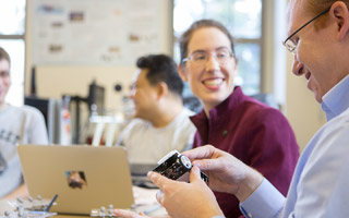 Faculty and students discussing at a table