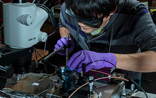 Student wearing gloves working with soldering gun