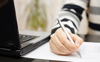 Person holding pen close to laptop