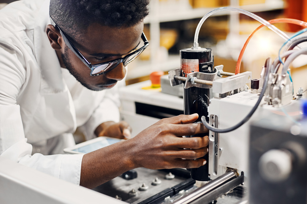  Man in a lab coat inspecting industrial machinery.