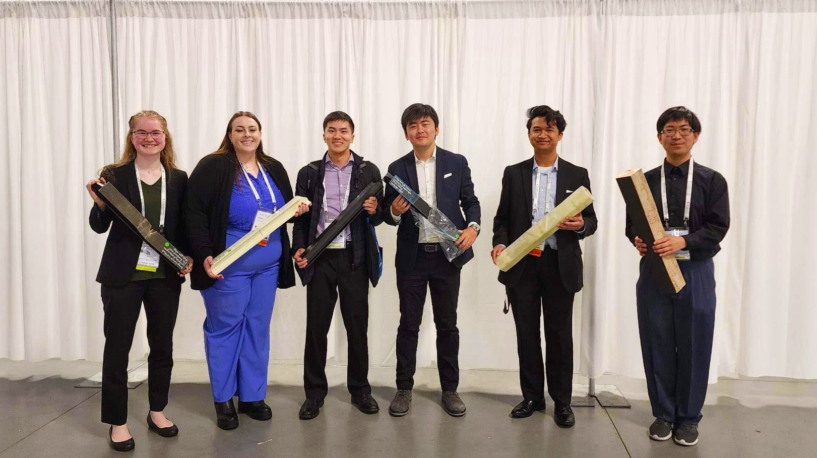 Six smiling students posing for picture holding their competition beams.