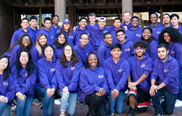 A group of students smiling by a campus fountain