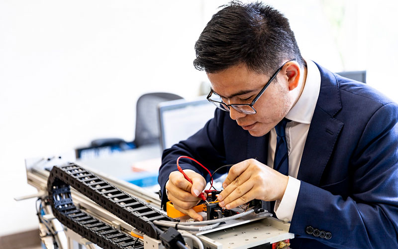 Person wearing suit soldering computing parts