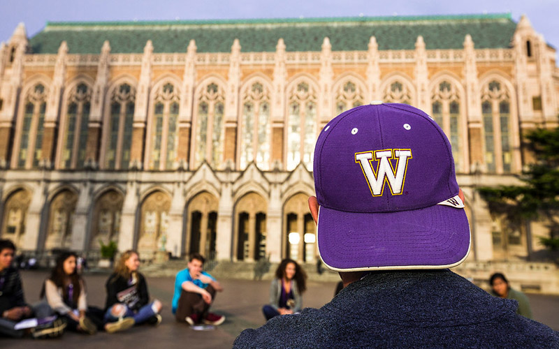 One student wearing W hat, sitting in a circle with other students