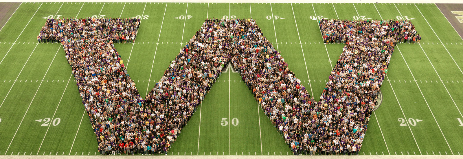 A group of people on a football field in the shape of a W