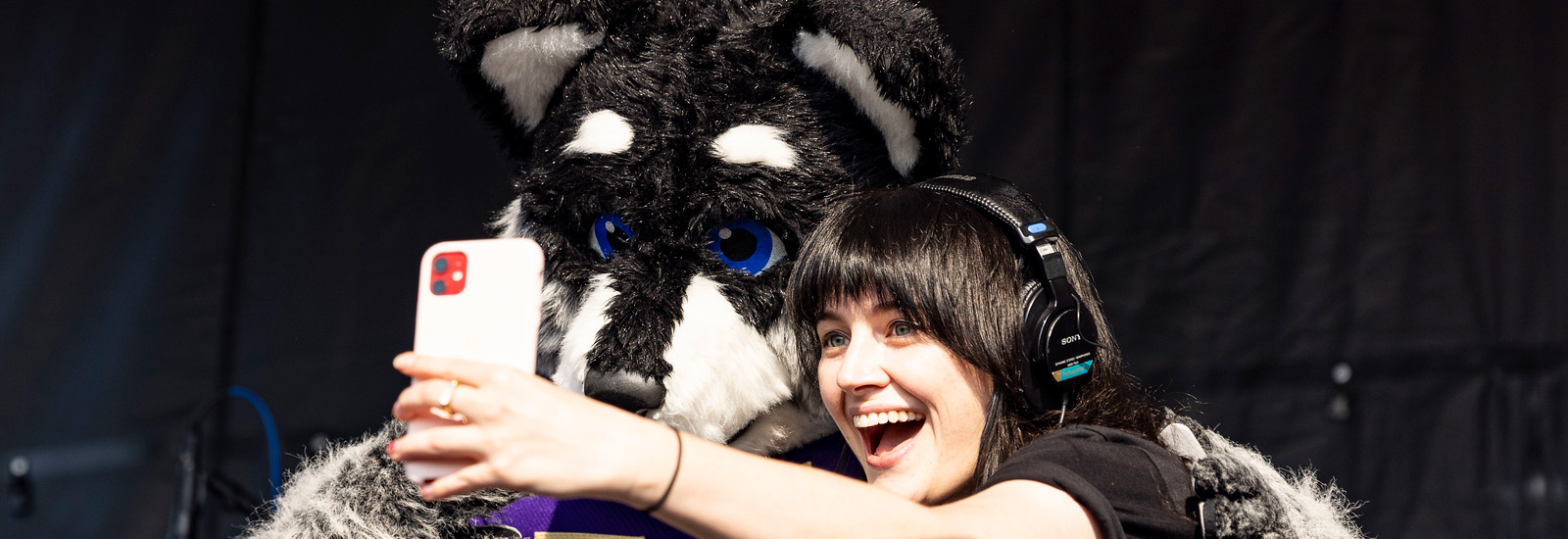 A student taking a selfie with the husky mascot