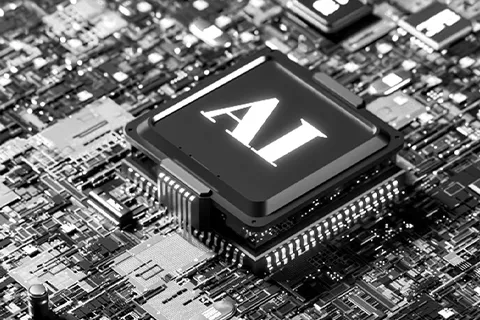 A black-and-white photo of a computer chip with the letters "AI" stamped on it, mounted to a motherboard