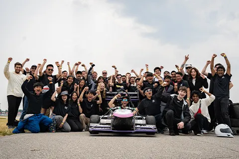 a group of people posing for a photo with a race car