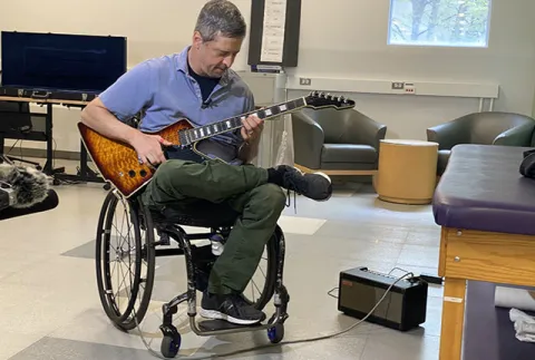 Jon Schlueter plays guitar in the lab of UW Medicine professor Chet Moritz.