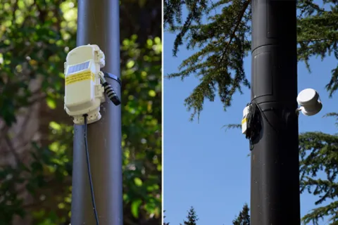 Close-up of utility poles with mounted electronic devices and cables in an outdoor setting