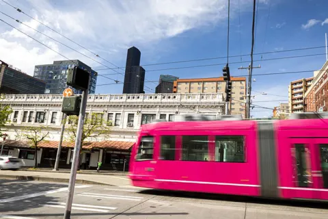 Seattle pink street car riding by a building