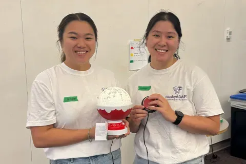 Jaelynn Hunt-Osburn and Maelynn Dank hold a switch-adapted toy that looks like a snow globe.