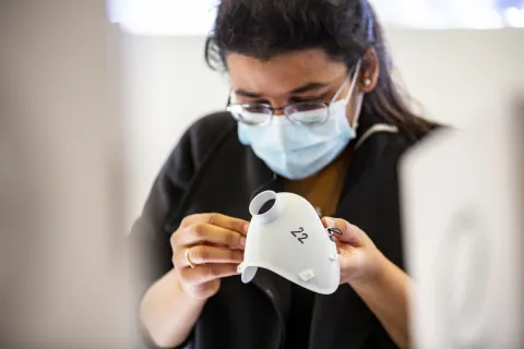 A student looking at a 3D printed medical mask prototype
