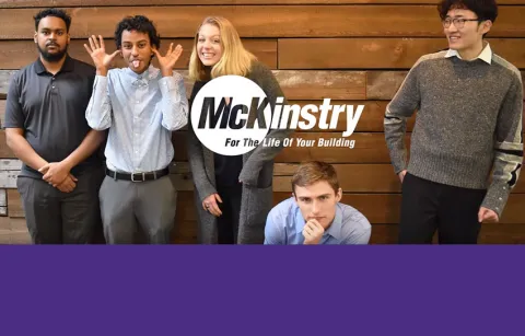 Five engineering students posing in front of a wooden wall