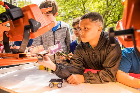 Students holding model cars and interacting with an exhibition