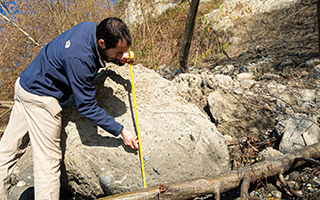 Person measuring large rock