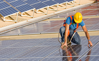 Person wearing hard hat working on solar panels